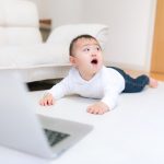 パソコンの前で振り返ろうとする赤ちゃん