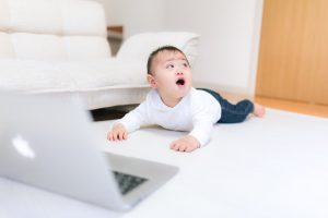 パソコンの前で振り返ろうとする赤ちゃん