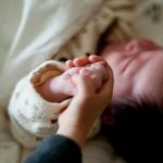 寝ている赤ちゃんの手を握る兄