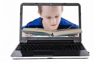 パソコンの画面に映る本を読む少年