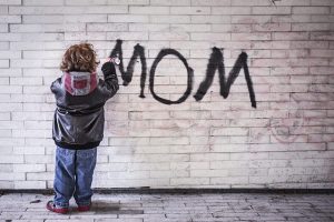 壁にママと書く少年