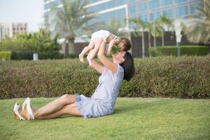 芝生の上で赤ちゃんを抱える母
